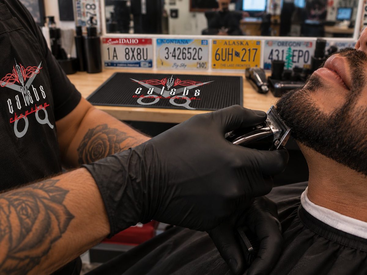 Caleb's Chopshop barber trimming a customer's beard with clippers